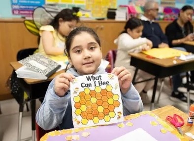 Child showing artwork in a preschool classroom at a daycare in Miami