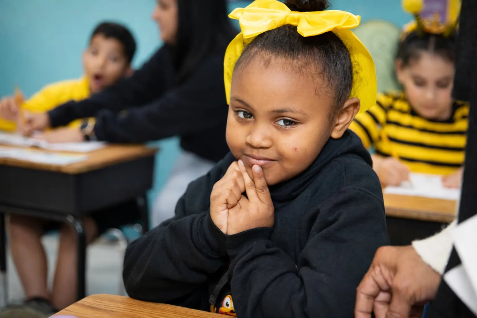 Student with a yellow bow smiling in class